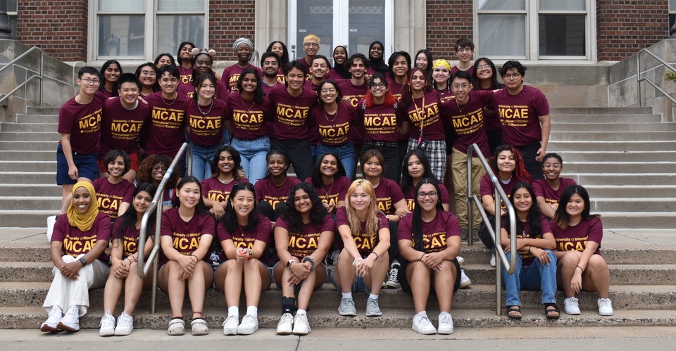 Image of a large group of students sitting on the steps of Appleby Hall wearing matching MCAE Kickoff 2022 shirts.